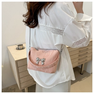 Détail d'un sac à bandoulière rose avec texture plissée et nœud décoratif argenté