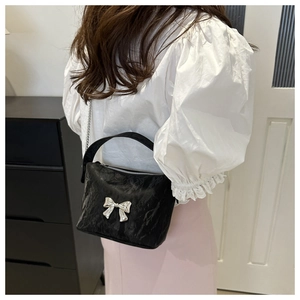 Détail du sac à main en PU plissé noir avec nœud argenté et bandoulière chaîne sur modèle