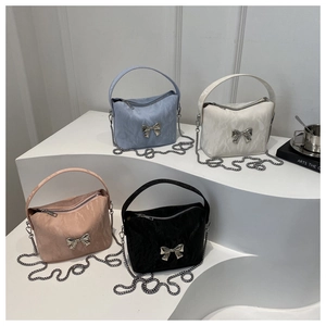 Detail view of four elegant bow-accented shoulder bags in blue, white, pink, and black