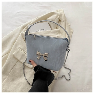 Detail of light blue bow handbag featuring ruffled texture and silver metal chain strap