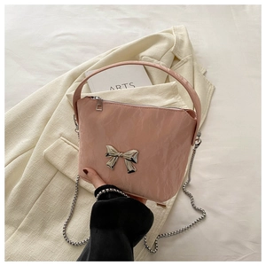 Detailed close-up of pink pleated handbag with silver metallic bow and chain strap