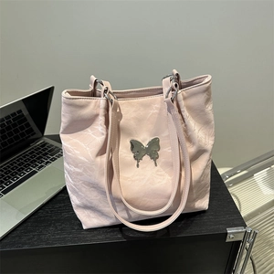 Sac cabas rose clair avec logo papillon en métal sur un bureau pour le travail quotidien