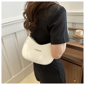 Detail of white minimalist half-moon baguette bag with golden buckle on a black dress