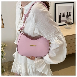 Detail of pink crescent bag showing knotted shoulder strap and gold hardware accents