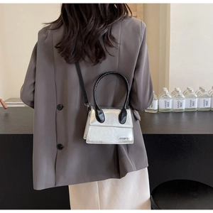 Detalle del bolso plateado metalizado con asas negras y el nombre de marca Jingpin