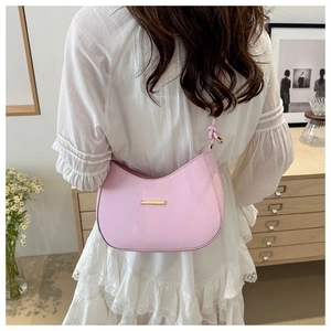 Detail of pink hobo bag with knotted shoulder strap and gold logo shown on a model