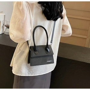 Vista trasera de una modelo con el bolso bandolera de cuero negro y detalle de logo