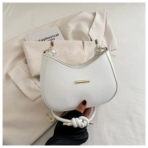 Detail of white leather crescent bag with gold metal trim and knotted shoulder strap