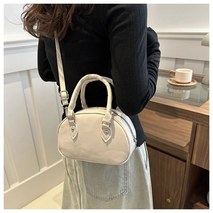 Sac Boston chic de couleur crème porté à l'épaule dans un intérieur élégant