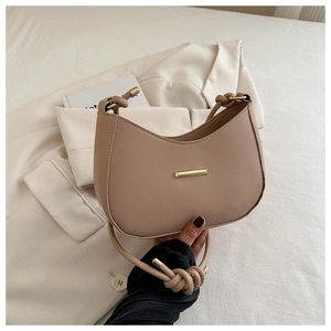 Detail of beige crescent underarm bag with gold metal buckle and knotted shoulder strap