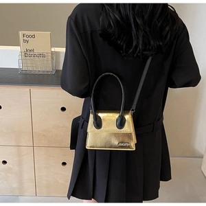 Detalle de mini bolso bandolera dorado metalizado con asas dobles y correa fina de hombro