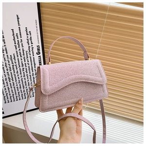 Close-up of pink woven glitter handbag featuring unique curved flap and gold metal clasp