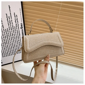Detail of champagne gold woven handbag featuring a wavy flap and soft metallic texture
