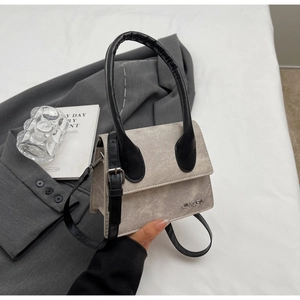 Detalle de bolso bandolera gris con logo JINGFIN junto a un traje y libro