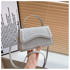 Detail of light grey sequin crossbody bag featuring woven texture and gold hardware