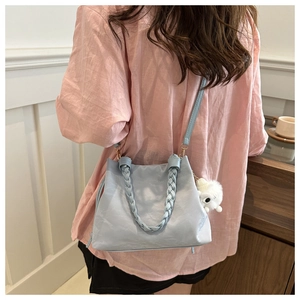 Détail du sac à main bleu clair avec poignée tressée et pendentif lapin en peluche blanc