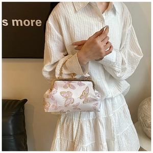 Détail du fermoir vintage et broderie papillon rose sur sac à main en soie blanche