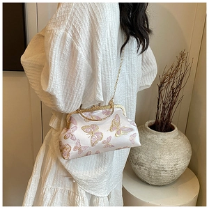 Détail d'un sac à main en satin blanc avec broderie papillon rose et dorée et chaîne en or