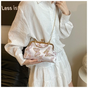 Detail of silk cross-body shell bag featuring pink butterfly embroidery and gold clasp