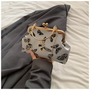 Detalle de bolso vintage gris con bordado de mariposas y cierre de marco de metal dorado