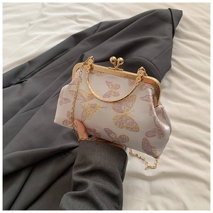 Detalle de bordados de mariposas en un bolso de fiesta blanco con cierre de boquilla