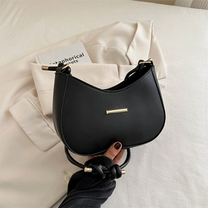 Chic black crescent hobo bag with knotted strap and gold hardware on white blazer