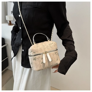 Detailed view of straw woven box bag with floral embroidery and gold chain strap