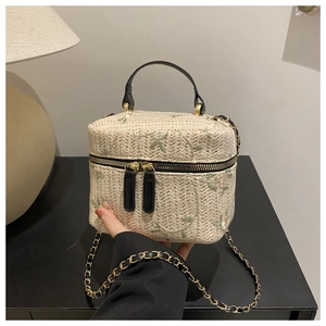 Detail of hand-woven straw box bag with delicate floral embroidery and gold-tone zipper