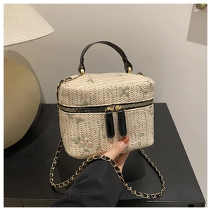 Detailed view of hand-woven straw box bag with pastel floral embroidery and chain strap