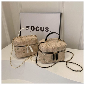 Detail of straw crossbody bags with floral embroidery and gold chain straps