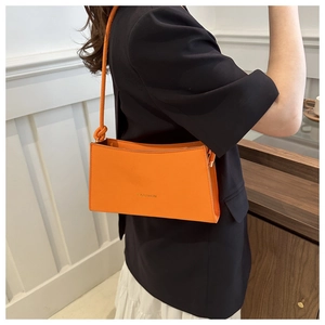 Détail du petit sac orange vif avec bandoulière nouée et logo embossé de mode élégante