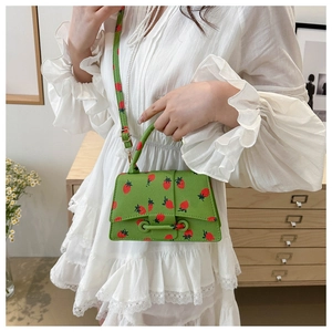 Gedetailleerd beeld van groene mini-handtas met aardbeienprint en unieke zandlopervorm