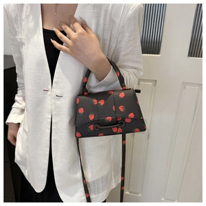 Close-up van mini trapezium handtas met aardbeienprint en lychee-leer textuur details