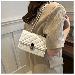 Détail de la texture cuir matelassé blanc et de la chaîne argentée du sac à bandoulière