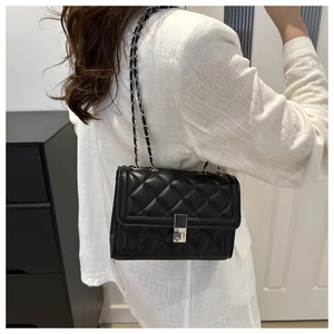Détail du sac à bandoulière matelassé noir avec chaîne argentée et fermoir en métal