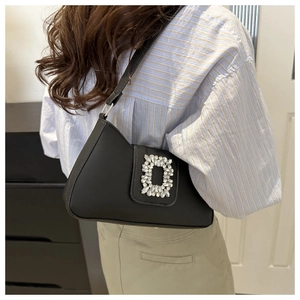 Detailed view of black leather underarm bag featuring a sparkling crystal rectangle buckle