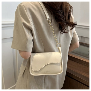 Détail d'un sac selle blanc cassé avec bandoulière chaîne dorée et rabat magnétique