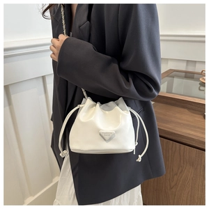 Close-up of white drawstring bucket bag with leather chain strap and triangle metal logo