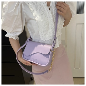 Détail du sac bandoulière lilas avec rabat ondulé et accents de chaîne dorée