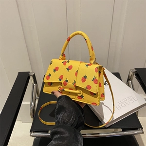 Mini gele crossbodytas met aardbeienprint en verstelbare riem in een stijlvolle setting