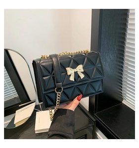 Detailed close-up of a quilted shoulder bag featuring a decorative gold metal bow clasp