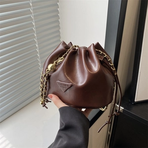 Minimalist dark brown drawstring bucket bag with gold chain strap and triangle logo