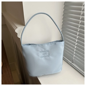 Detail of light blue nylon handbag with onwards and upwards embroidery in natural light