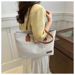 Detail of the high-quality canvas tote bag with reinforced brown leather handles and tag