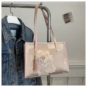 Gros plan sur la broderie florale du cabas en satin rose avec pompon élégant
