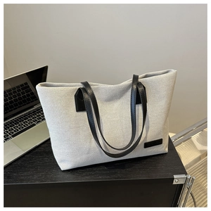 Detail of canvas tote bag with black leather handles on desk showing textile texture