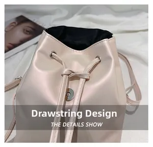Detail view of cream bucket bag showing drawstring closure and magnetic metal buckle