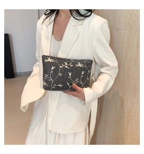 Detail of grey embroidered floral handbag held by model in white suit for business style