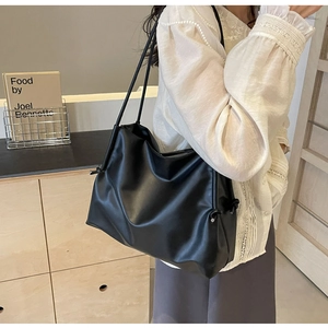 Detail of minimalist black large capacity tote bag with side drawstring knot and soft PU texture