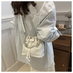 Vue détaillée du sac seau blanc à cordon avec poignée élégante en perles et bandoulière